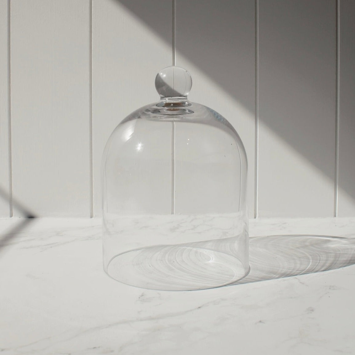 Glass Dome Small pictured in front of a white slat wall